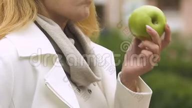 漂亮的女士在<strong>午餐时间</strong>吃新鲜的绿色苹果健康小吃，营养