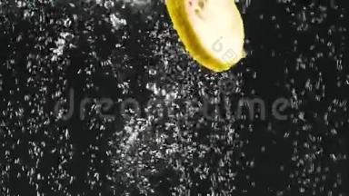 新鲜柠檬片落入水中的黑色背景。 柠檬在水中有气泡。 有机食品，健康