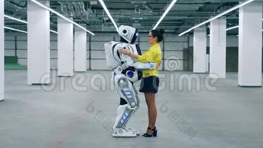 一位女士拿着一个半机器人和它说话
