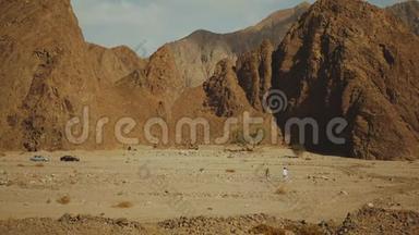 一群<strong>游客</strong>在炎热的沙漠中沿着岩石峡谷散步。 沙漠岩石背景，埃及，西奈，慢动作，全<strong>高清</strong>