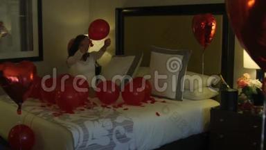 快乐的新娘坐在床上拿着气球