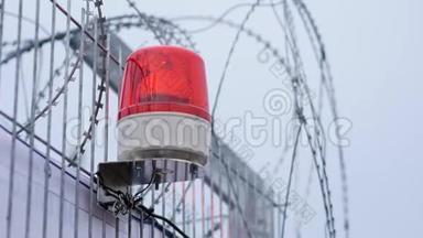 警告旋转警笛闪烁的信号灯在一天。 带红色警报灯的铁丝网