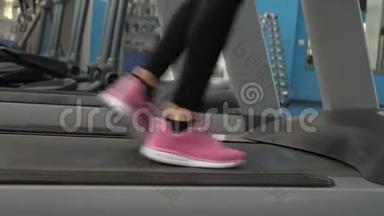 体育生活理念。 穿运动鞋的女孩的腿沿着跑步机走。 特写镜头。 加强腿部肌肉