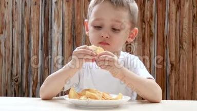 一个孩子喜欢吃薯片，而坐在一张桌子上，背景是一堵木墙。