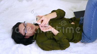 这位女博主躺在床上，触摸她的智能手机屏幕，<strong>在家</strong>里<strong>上网</strong>。