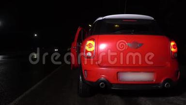 女人从一辆红色的车出来，晚上在高速公路上<strong>打开后备箱</strong>