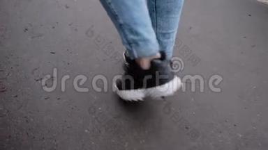 那个女孩在潮湿的沥青上绕着城市走来走去。 特写少女`脚踩在地上.. 回放缓慢。