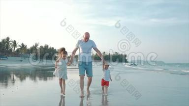 幸福的父亲、女儿和儿子在日落时在海滩上玩和玩。 动作缓慢。 幸福家庭