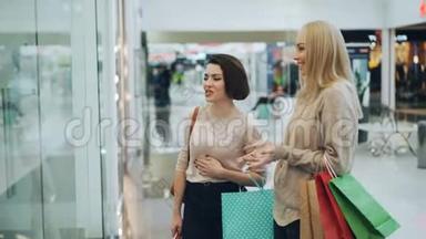 快乐的女孩在商场里聊天，谈论着新的内衣系列，指着人体模型上的衣服