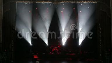 红色和白色的聚光灯照亮了黑暗中空荡荡的舞台上的鼓。