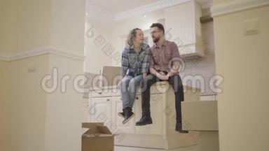 一对幸福的年轻夫妇坐在一间新公寓的厨房桌子上，讨论房子的<strong>布局</strong>。 <strong>家庭</strong>
