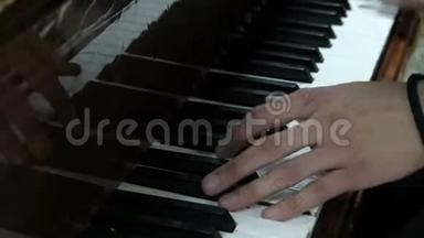 那个人弹钢琴。 一个年轻人的手按着乐器的白键和黑键。 一位年轻的钢琴家