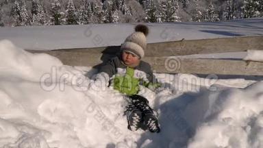 冬天，小可爱的男孩在外面的雪地里玩耍。 背景是一片雪林.. 这个男孩很高兴。 慢慢