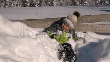 冬天，小可爱的男孩在外面的雪地里玩耍。 背景是一片雪林.. 这个男孩很高兴。 慢慢