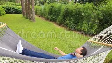 在吊床上放松和微笑的人，带吊床的夏日花园度假放松