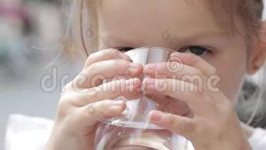 一个小可爱的女孩用杯子喝纯净水