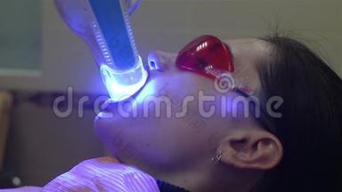 年轻女子在牙科医生办公室用紫外线`机器进行紫外线<strong>美</strong>白.