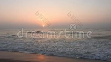 浪漫的日出在热带海滩上，有红色的金色光芒。 海浪与浪漫的日落与海浪。 海浪