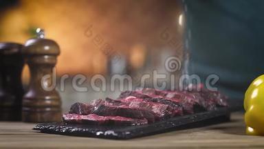 切片烤肉放在黑摊上.. 厨师用手撒红胡椒和盐。 特写，慢动作..