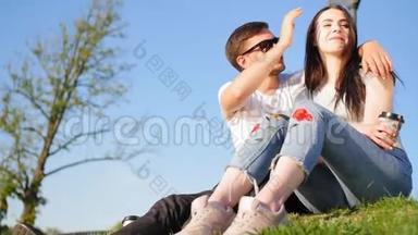 浪漫的<strong>夫妻</strong>喝咖啡，笑着坐在池塘附近的绿草上。 <strong>夫妻</strong>信任、爱情和幸福的概念