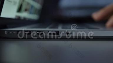 近距离直接拍摄的手快速插入白色USB电缆到笔记本电脑在黑桌背景。
