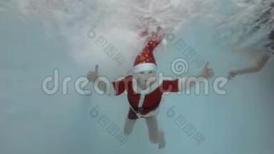 一个小男孩穿着圣诞老人的衣服在水池里的喷水池里游泳，他的手臂伸出