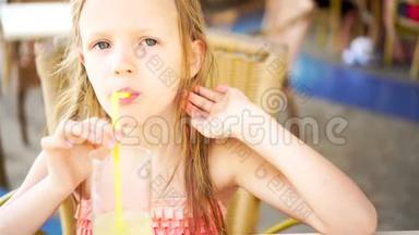 可爱的小女孩坐在餐桌旁喝着新鲜果汁的画像