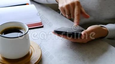 智能<strong>手</strong>机在妇女<strong>手</strong>中，咖啡和笔记本在桌子上。 <strong>关门</strong>