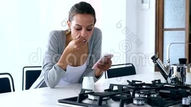 漂亮的年轻女人在家吃酸奶的时候用手机发信息。