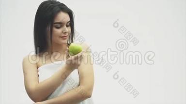 白色背景上一个年轻迷人的女孩的肖像。 指导和检查绿色苹果。 孤立于白色