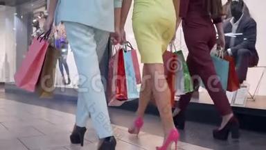 周末购物，穿着五颜六色衣服的时髦女孩在商场的商店附近高跟鞋散步