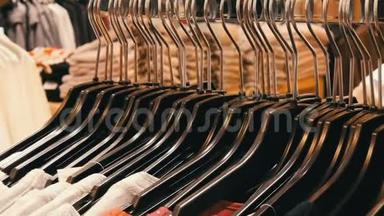 许多不同颜色`妇女的衣服挂在衣架上，躺在一家服装店的货架上。
