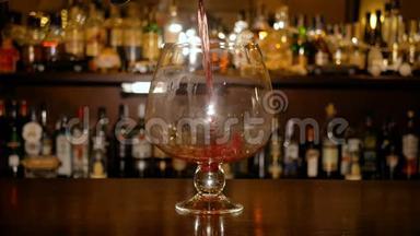 热葡萄酒倒入一个大玻璃杯的背景上的酒吧橱柜与瓶子。 煮木果酒。