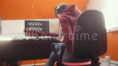 一个戴着耳机的音乐家坐在录音室的电脑旁录制一首歌
