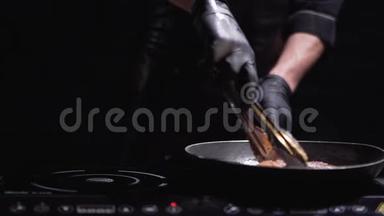 穿着黑衣服和手套的厨师在现代化的电炉上为汉堡准备肉