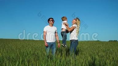 幸福的家庭：爸爸妈妈和儿子穿着白色的t<strong>恤衫</strong>和牛仔裤在田野里跳着笑