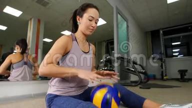 培训。 <strong>一个</strong>年轻的女人坐在<strong>地板上</strong>，用<strong>一个</strong>球训练她的手。 健身房