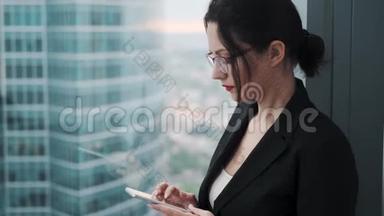 年轻女子站在摩天大楼的高楼层上使用智能手机