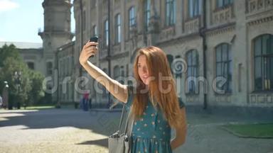 妩媚的姜姑娘自拍照，微笑着，站在街上，背景是建筑，快乐而快乐