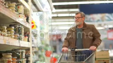 成熟的男人在超市买罐头花菜。 健康食品、现成沙拉、超市美食