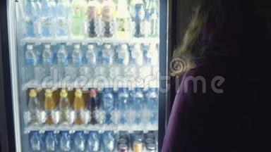 从穿紫色外套的年轻女人的背部看，从自动<strong>售货机</strong>上选择饮料。 库存录像。 饮料自动<strong>售货机</strong>