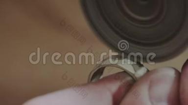 男金匠手正在抛光一个金环，用专业的抛光工具。 手工制作或手工制作。 生产