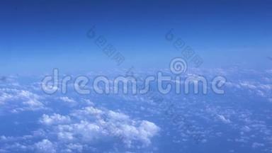 阳光明媚的天空和蓬松的云层从窗户飞机上看到。 从飞行飞机到蓝天白云的视野