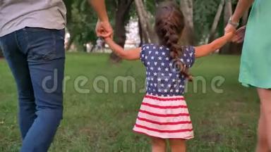 年轻的一家人夏天在公园里散步，抱着女儿，玩着概念