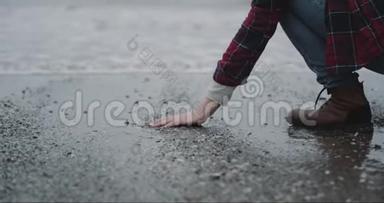 雨天，站在海边的人，手上拿着一些湿沙，把湿沙从手里<strong>扔下</strong>来