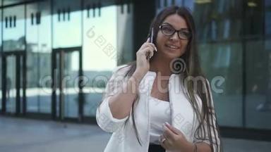 美丽的年轻首席银行家女士站在办公楼的后台打电话。