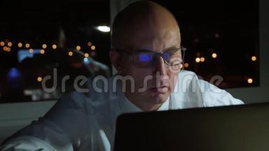 戴眼镜的行政商人晚上看手提电脑