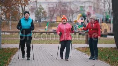 一位幸福的老年妇女发出手势，两位老年妇女开始用北欧的拐杖走路