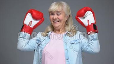 积极的退休妇女戴着拳击手套举手，成功的概念，<strong>信念</strong>