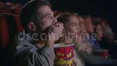 粗鲁的男人在电影院吃爆米花。 在电影院里粗鲁的举止